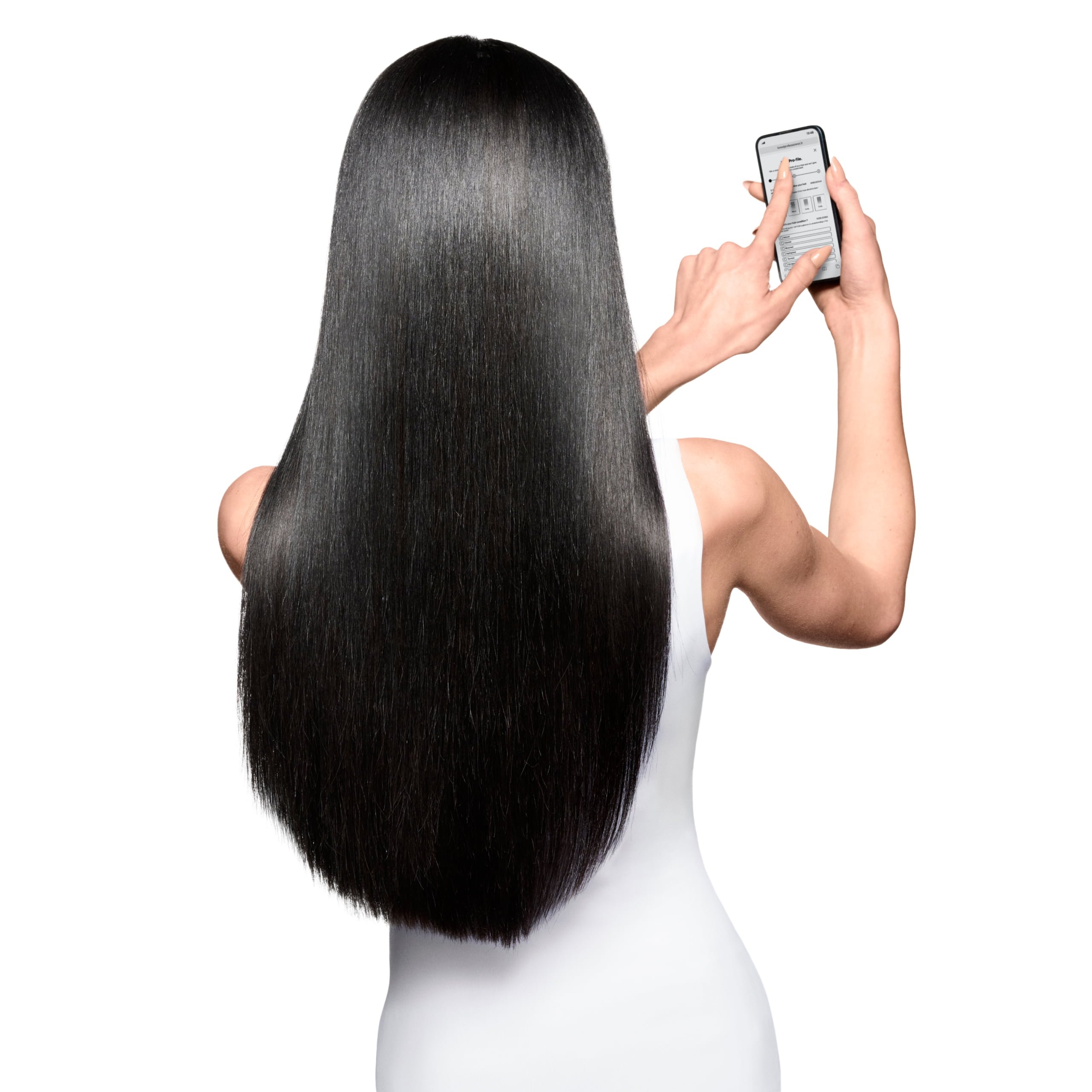 Mulher usa o celular para acessar um aplicativo de diagnóstico capilar, que ajuda a personalizar a rotina ideal de cuidados com os cabelos.