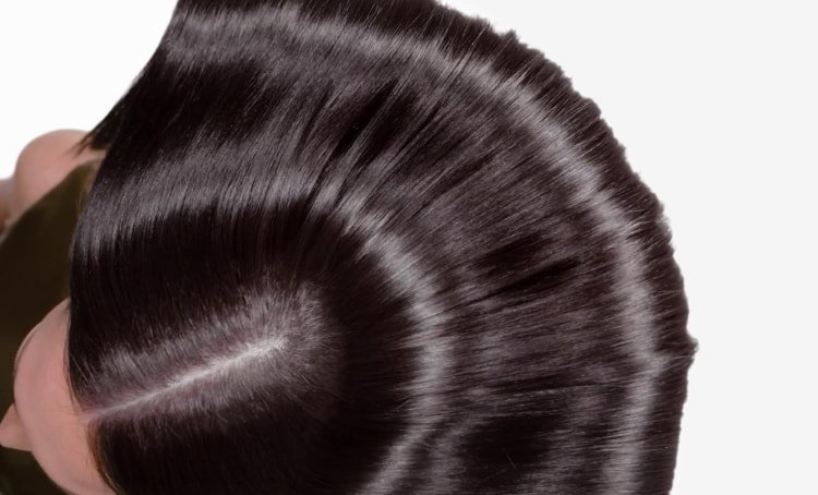 Woman with long, shiny hair illustrating the visible results of a well-performed anti-damaged hair care routine with smoothness and shine.