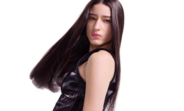 Keratin treatment in progress on a woman’s hair, changing frizzy texture into smooth, straight, fluid, and shiny lengths.