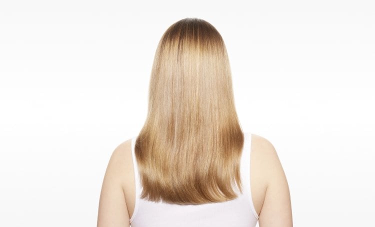 Woman with visibly repaired hair, showing improved strength, smoothness, and shine after following the ultimate guide to repairing damaged hair.&nbsp;