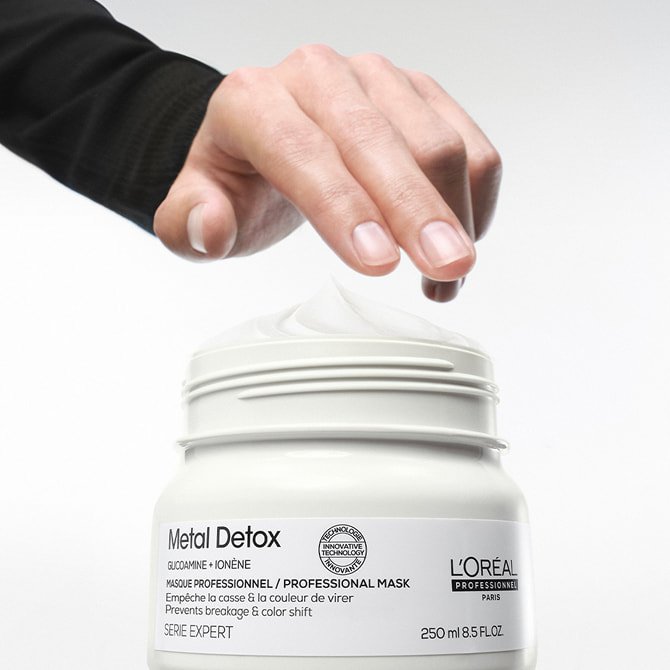 Hand dipping into a professional hair mask for every type of hair to prevent breakage and maintain vibrant salon color. 